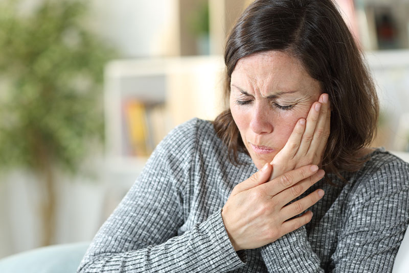 woman holding jaw in pain